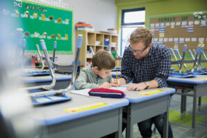 Teacher helping elementary student in classroom